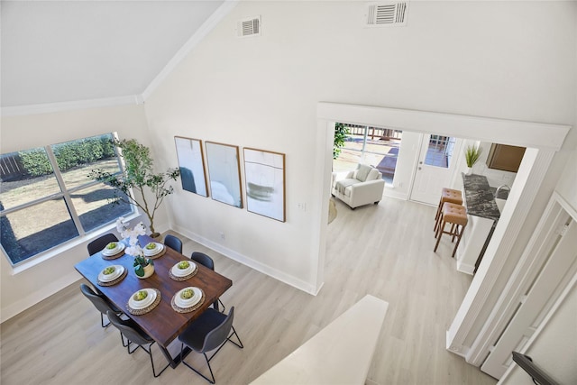 living area with light wood-type flooring, baseboards, visible vents, and crown molding