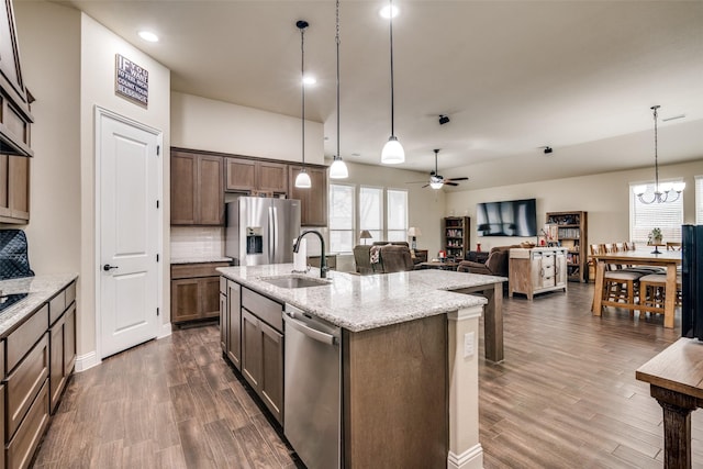 kitchen featuring dark wood-style flooring, a sink, decorative backsplash, appliances with stainless steel finishes, and ceiling fan with notable chandelier