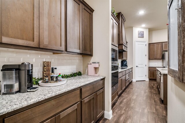 kitchen with dark wood-type flooring, tasteful backsplash, recessed lighting, stainless steel oven, and light stone countertops