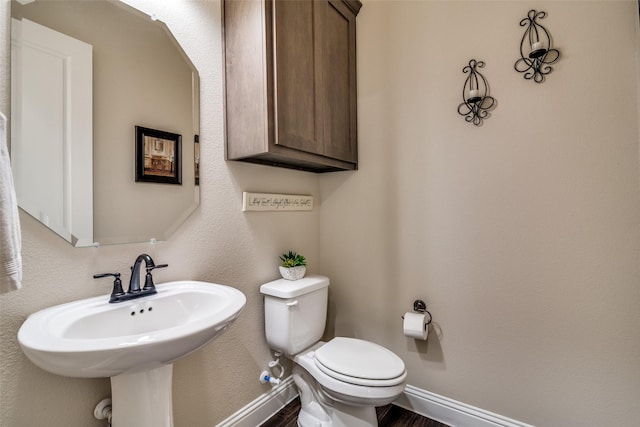 half bath featuring baseboards and toilet