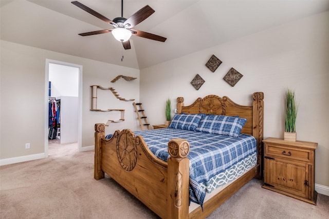 bedroom with a walk in closet, a ceiling fan, baseboards, light colored carpet, and vaulted ceiling
