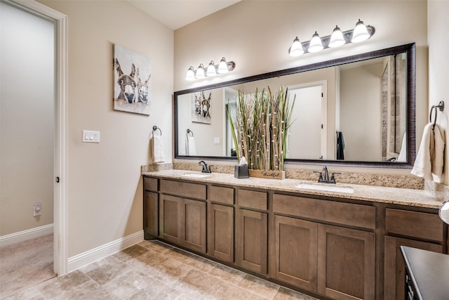 full bathroom featuring double vanity, baseboards, and a sink