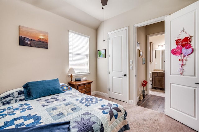 carpeted bedroom with baseboards, ensuite bath, and vaulted ceiling