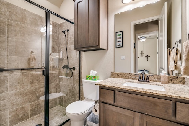bathroom featuring a ceiling fan, vanity, toilet, and a shower stall