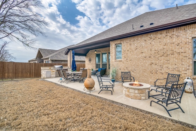 exterior space with a fire pit, ceiling fan, fence, and an outdoor kitchen