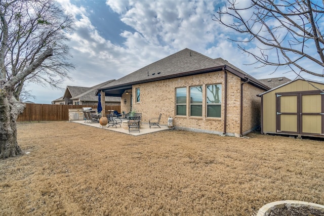 back of house featuring a storage unit, a patio, brick siding, and an outdoor structure