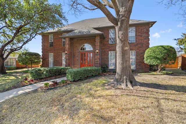 view of front of property with a front yard, french doors, and brick siding