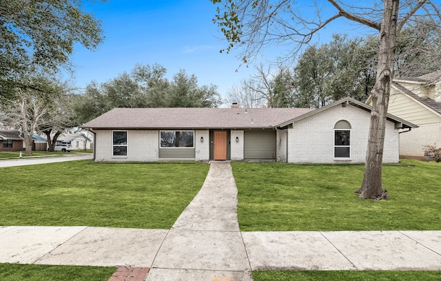 view of front of home with roof with shingles, a chimney, a front lawn, and brick siding