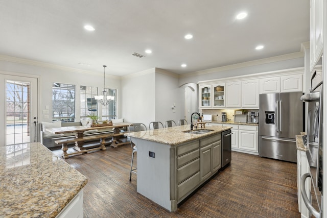 kitchen featuring white cabinetry, an island with sink, stainless steel fridge with ice dispenser, a sink, and a kitchen bar