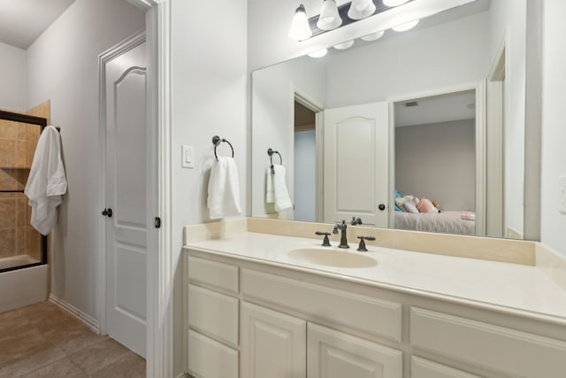 ensuite bathroom with tile patterned floors, connected bathroom, vanity, and shower / bath combination with glass door