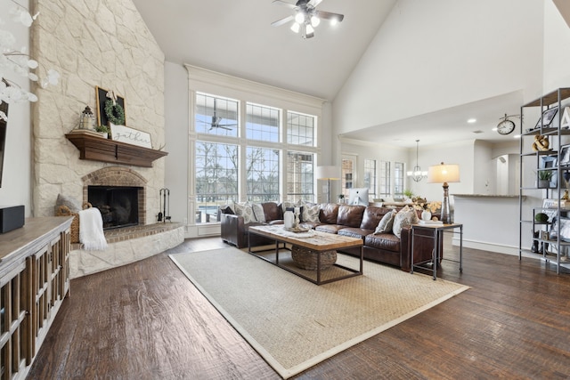 living room with a stone fireplace, ceiling fan with notable chandelier, a healthy amount of sunlight, and wood finished floors