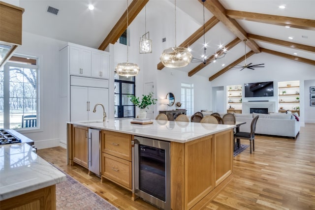 kitchen with a spacious island, wine cooler, open floor plan, hanging light fixtures, and a sink