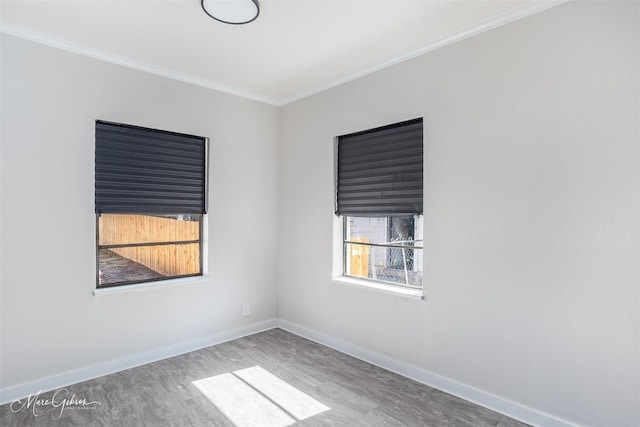 spare room with crown molding, wood finished floors, and baseboards