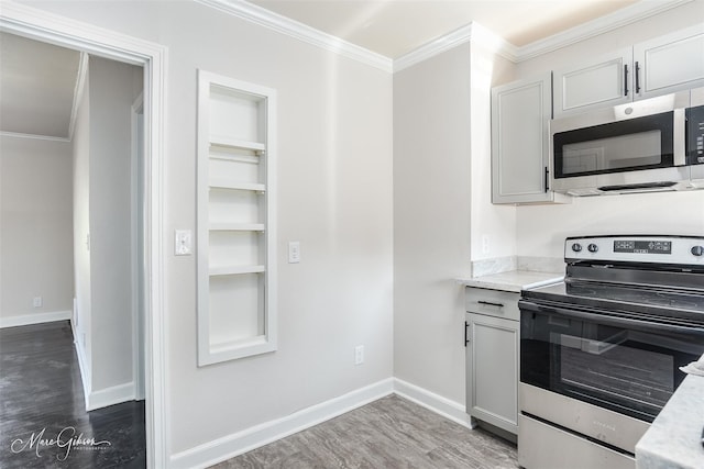 kitchen featuring appliances with stainless steel finishes, dark wood finished floors, ornamental molding, and baseboards