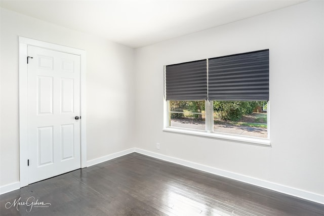 empty room featuring baseboards and dark wood-style flooring