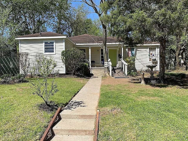 view of front of house with covered porch, a front lawn, and fence