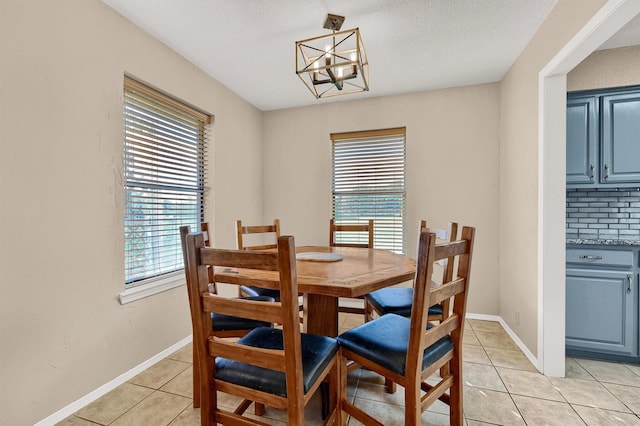 dining area featuring light tile patterned flooring, baseboards, and an inviting chandelier