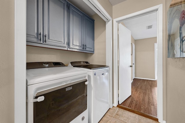 washroom featuring cabinet space, light tile patterned floors, baseboards, visible vents, and independent washer and dryer