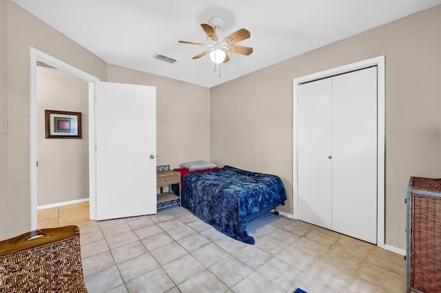 bedroom featuring light tile patterned floors, visible vents, baseboards, a ceiling fan, and a closet