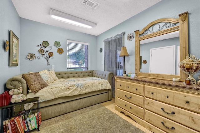 bedroom with light carpet, visible vents, and a textured ceiling