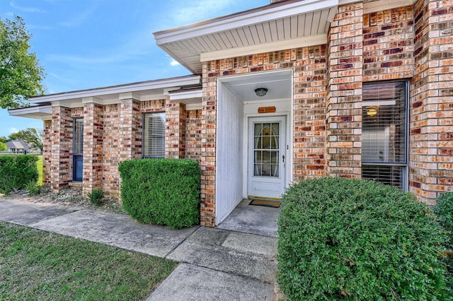 view of exterior entry featuring brick siding