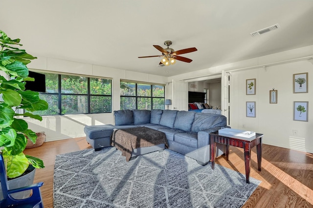 living area featuring ceiling fan, wood finished floors, and visible vents