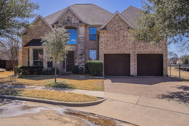 view of front of property with brick siding, a shingled roof, an attached garage, fence, and driveway