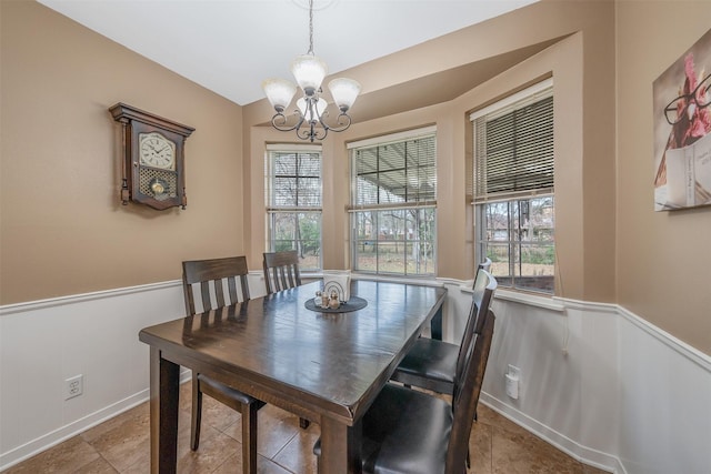 dining space with a wainscoted wall and an inviting chandelier