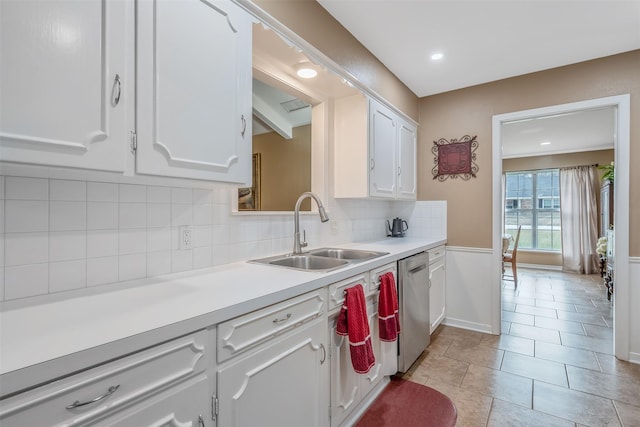 kitchen with a sink, white cabinetry, light countertops, backsplash, and dishwasher