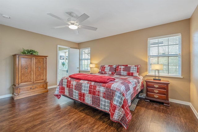 bedroom featuring dark wood-style floors, ensuite bathroom, a ceiling fan, and baseboards