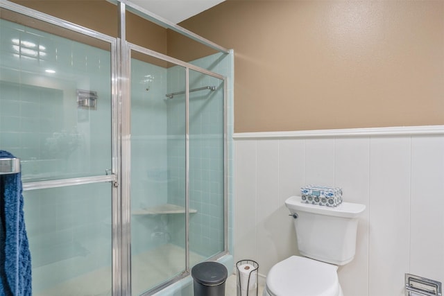 full bathroom with a wainscoted wall, a tile shower, and toilet