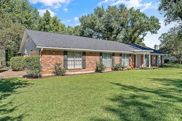 ranch-style house with a garage, brick siding, roof with shingles, and a front yard