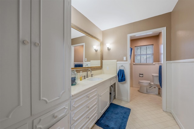 full bath featuring tile patterned flooring, a wainscoted wall, vanity, and toilet