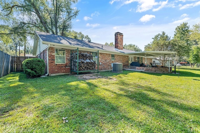 back of house featuring brick siding, a chimney, fence, and a lawn