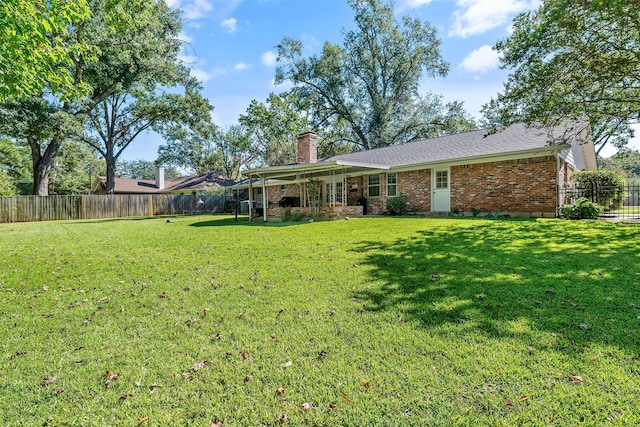 rear view of property featuring a fenced backyard, a chimney, a lawn, and brick siding