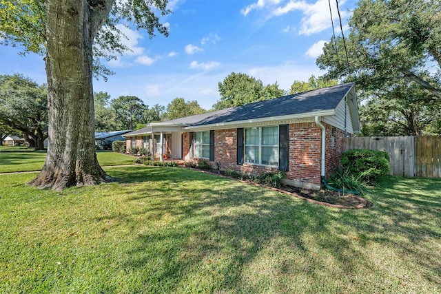 ranch-style house with a front yard, brick siding, and fence