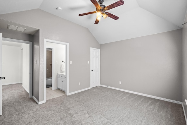 unfurnished bedroom with baseboards, visible vents, light colored carpet, lofted ceiling, and ensuite bathroom