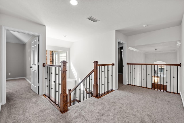 hall featuring lofted ceiling, visible vents, carpet flooring, and an upstairs landing