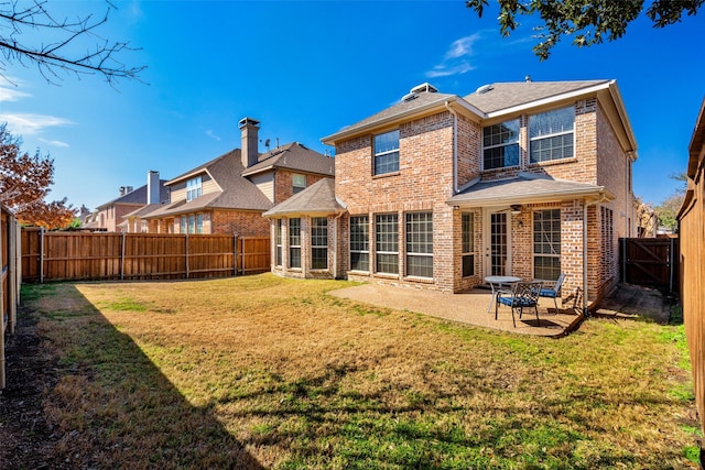 rear view of house featuring a yard, a patio, brick siding, and a fenced backyard