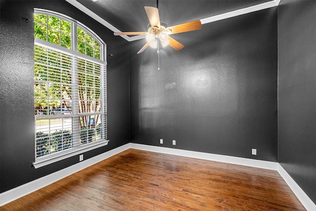 spare room with a ceiling fan, plenty of natural light, baseboards, and wood finished floors