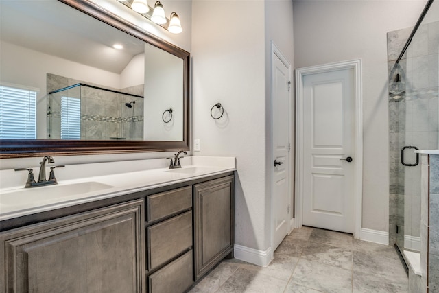 full bath featuring a sink, a shower stall, baseboards, and double vanity