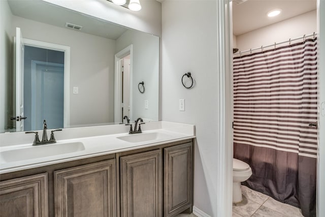 bathroom with visible vents, a sink, toilet, and double vanity