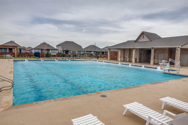 community pool with a patio area, a residential view, and fence