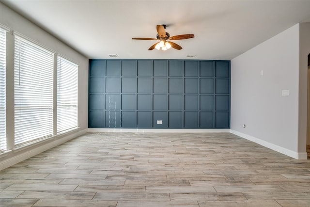 spare room featuring ceiling fan, light wood finished floors, visible vents, and baseboards