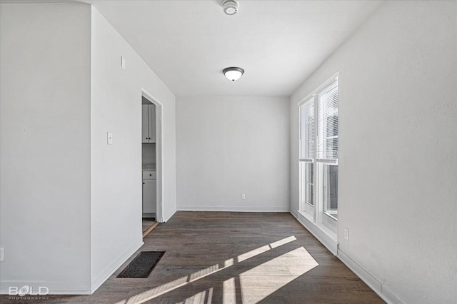 spare room with dark wood-style floors, baseboards, and visible vents