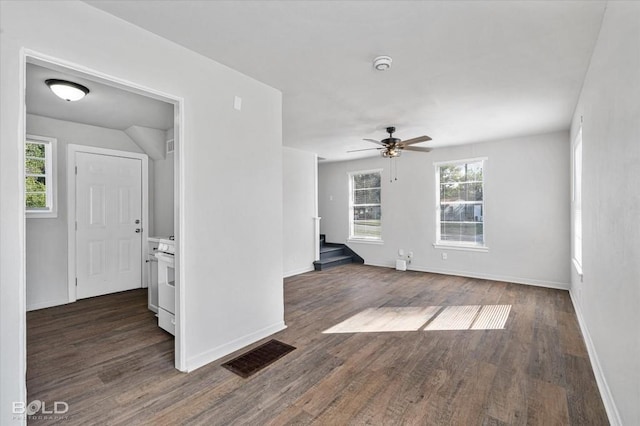 empty room with a healthy amount of sunlight, baseboards, visible vents, and dark wood-type flooring