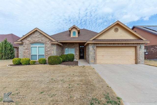 view of front of house featuring brick siding, roof with shingles, concrete driveway, a garage, and a front lawn