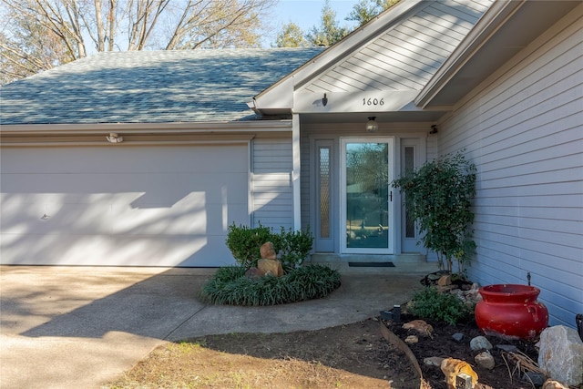 property entrance featuring a shingled roof, driveway, and an attached garage