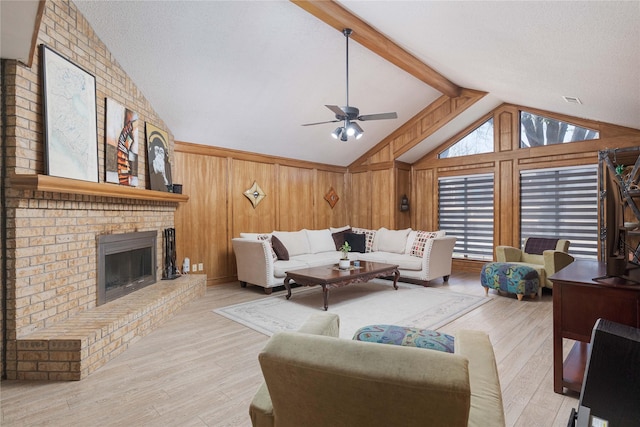 living area featuring lofted ceiling, wood walls, wood finished floors, a ceiling fan, and a brick fireplace