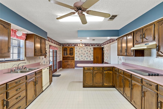 kitchen with black electric stovetop, light countertops, white dishwasher, a sink, and wallpapered walls